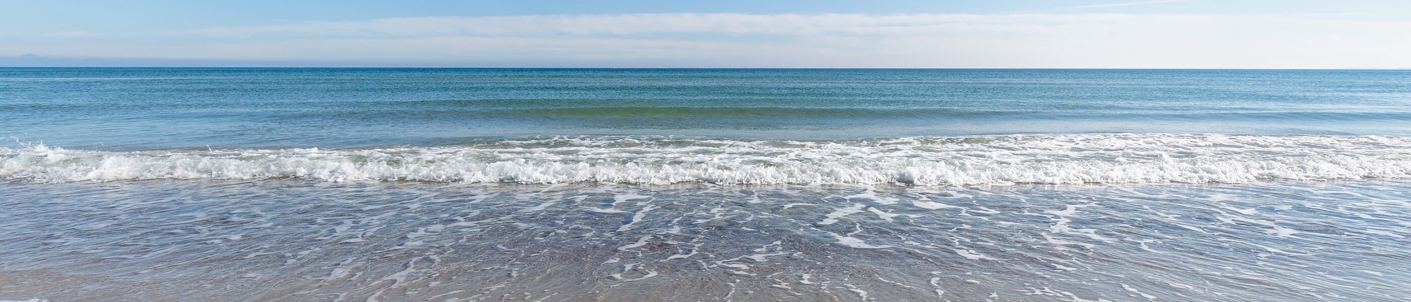 Weites Meer mit leichter Brandung und hellem Horizont